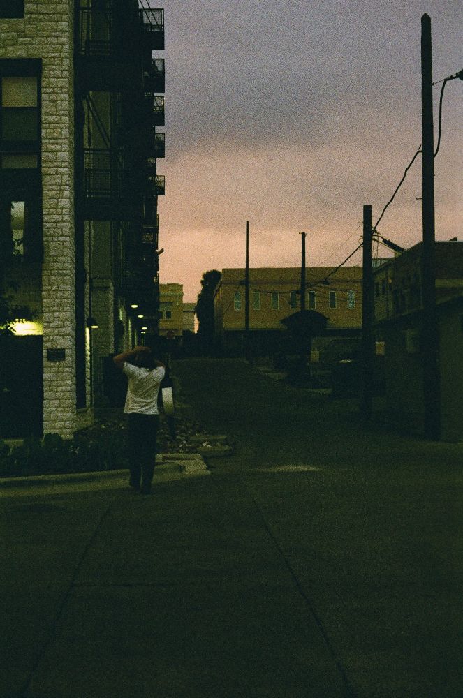 Evening photo of a guy walking up a roadway in town.