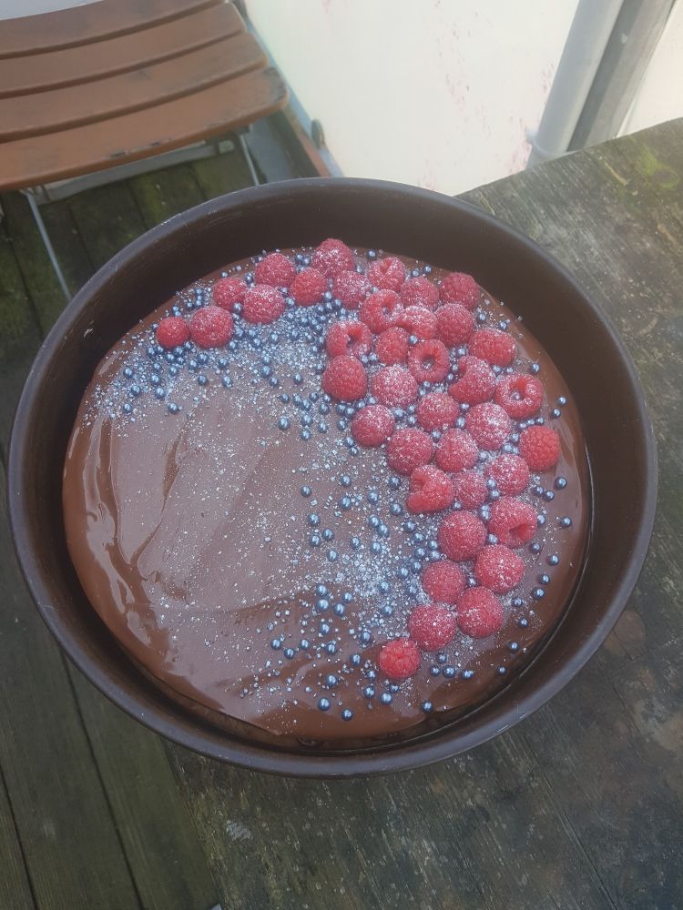 Vegane Schokotorte mit Himbeeren und Silberzuckerperlen dekoriert