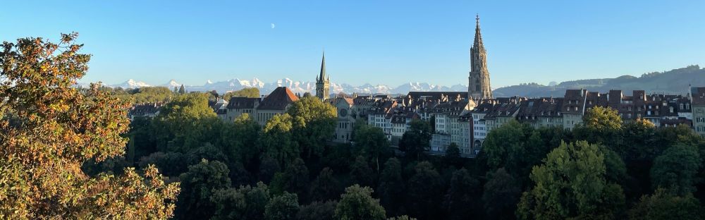 Panorama view onto the old town of Bern and the alps behind it on a sunny day.