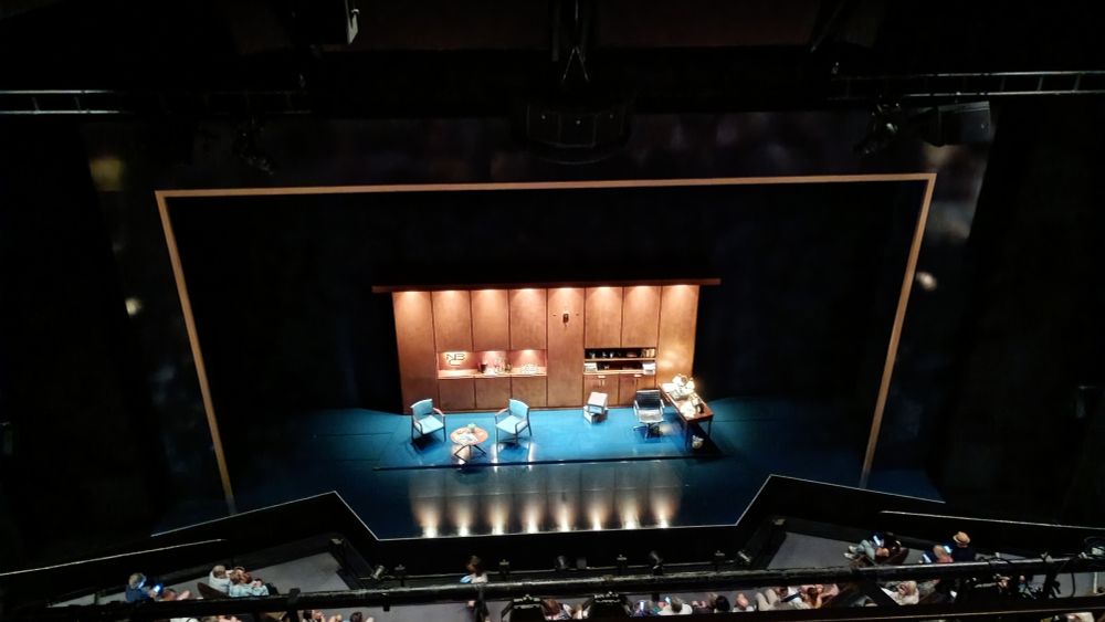 Photo from the back row of Barbican theatre for Good Night Oscar. 1960's staging with wooden panelling in an office set up
