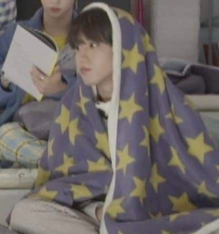 han sitting with a starry blanket draped over him like a cloak, looking sad