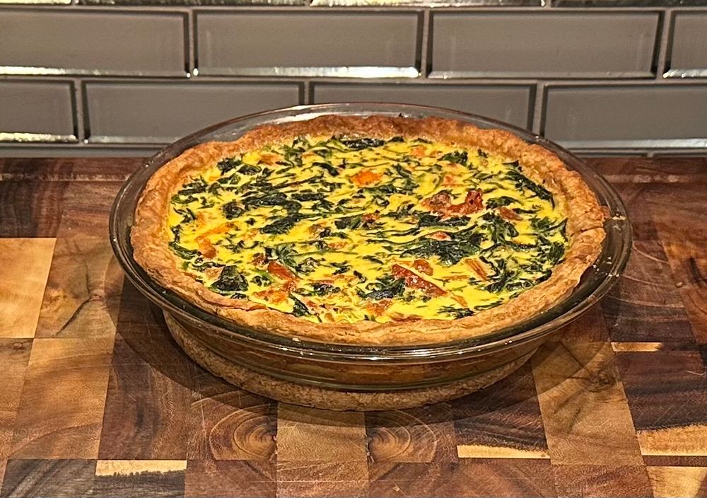 It is a quiche. Spinach and sun-dried tomatoes visible. 
