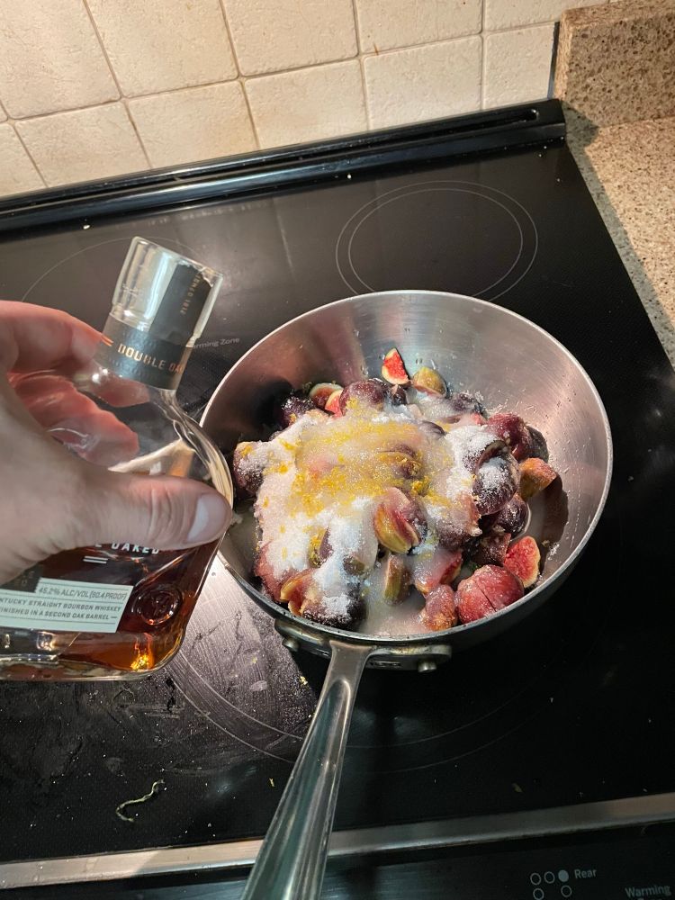 Pouring bourbon on the assembled figs and lemon zest