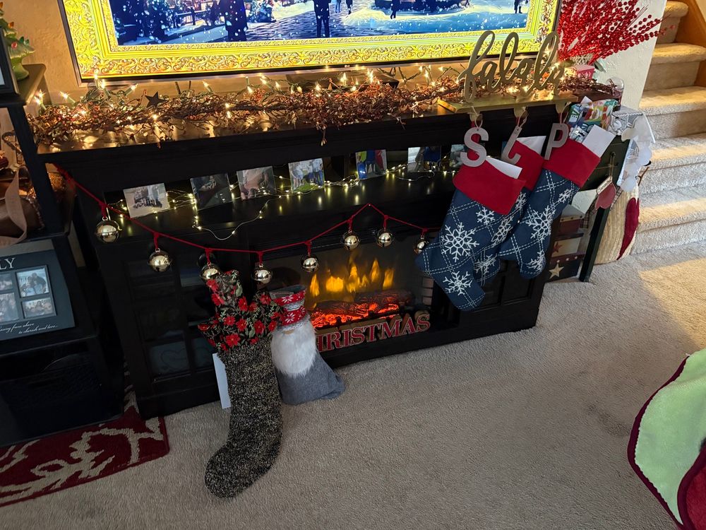 Stockings loaded with presents in front of a fake fireplace 