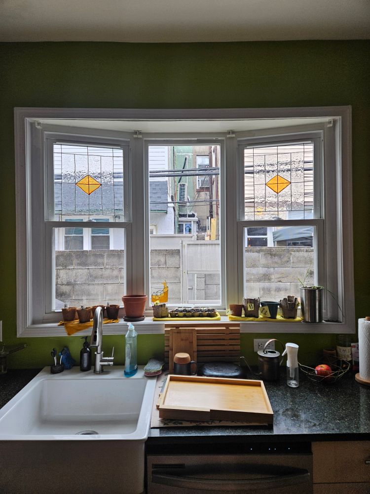 Bay window looking at an alley with two windows of faux stained glass, consisting of a geometric pattern with orange diamonds in the middle