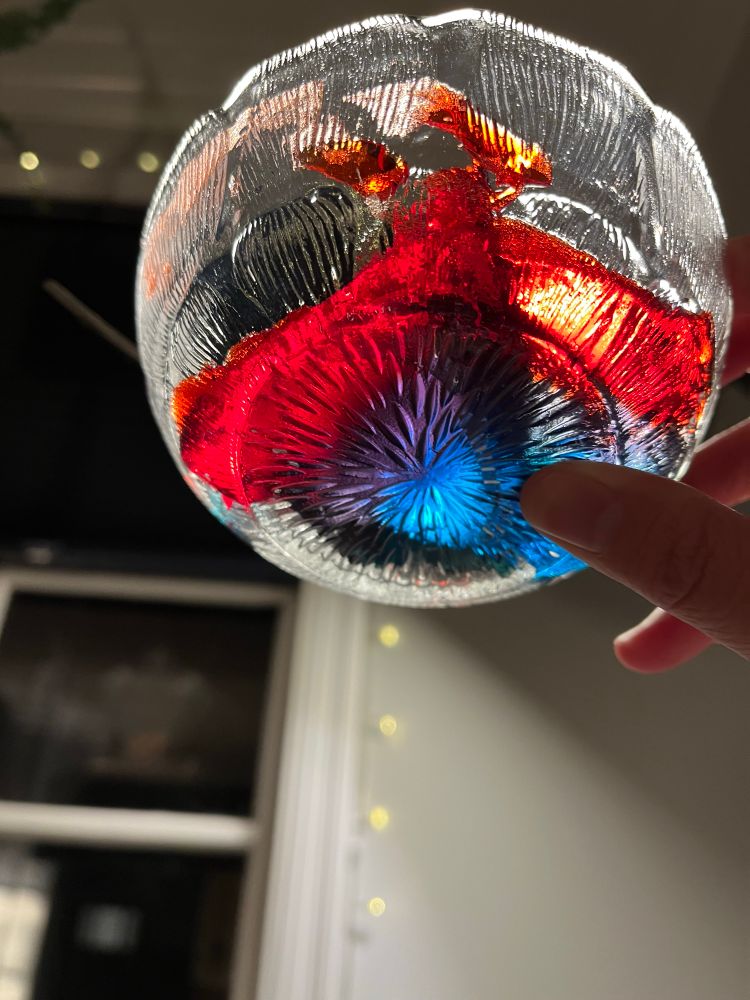 Underside of a glass bowl with red, purple, and blue Jello. 