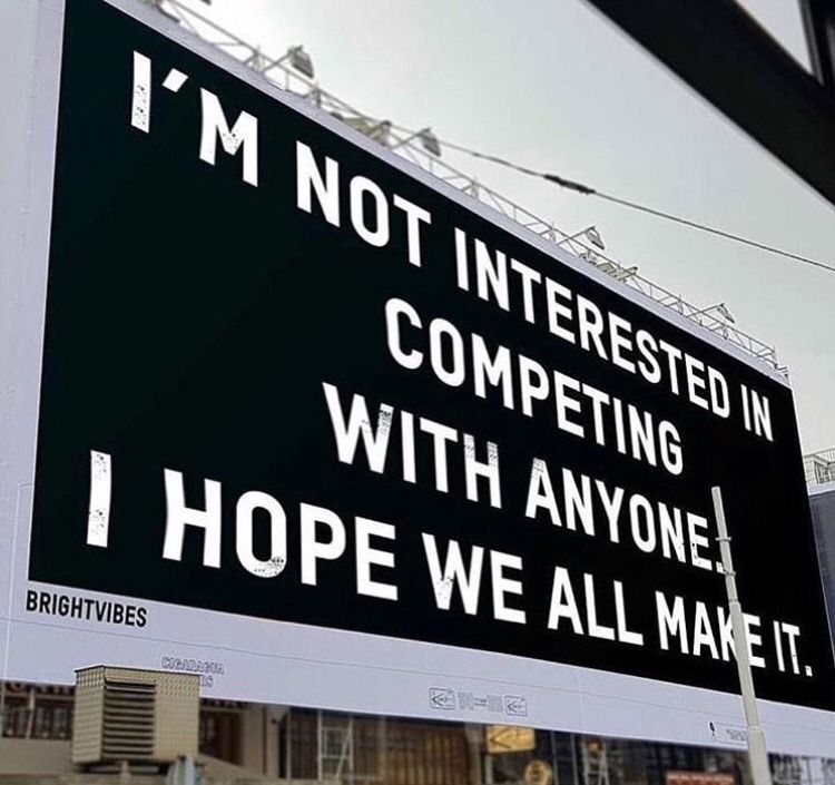 A billboard painted black with white text that says 'I'm not interested in competing with anyone. I hope we all make it.'