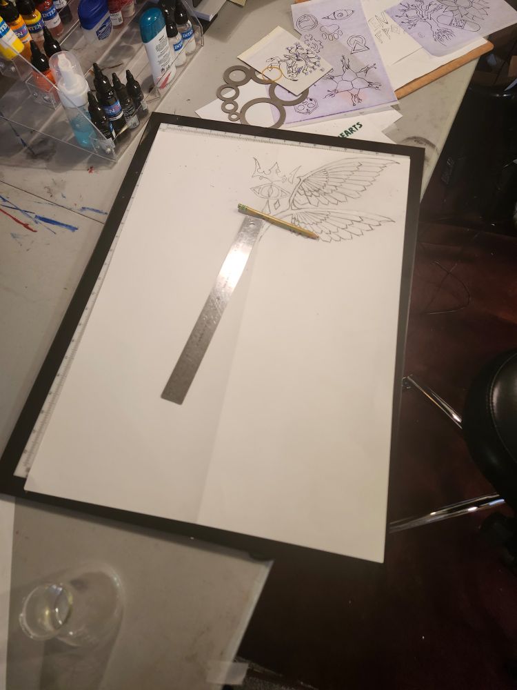 An A2 paper sheet with the first phases of a fullsize back tattoo in progress. 