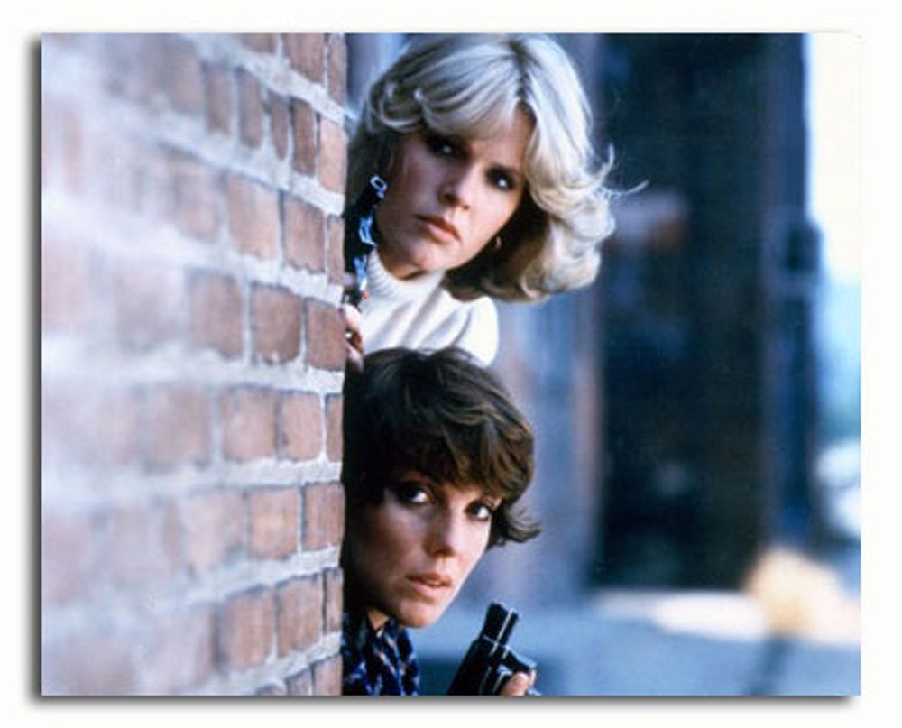 Cagney and Lacey peering round a wall. Both have guns. 