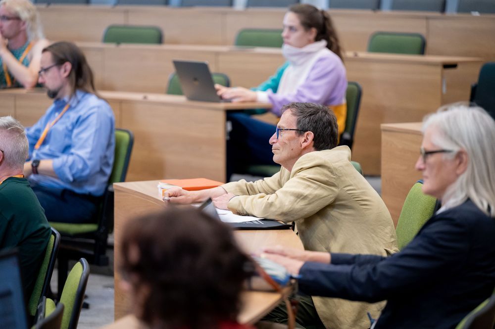 people sat in a session room making notes or sat listening. 