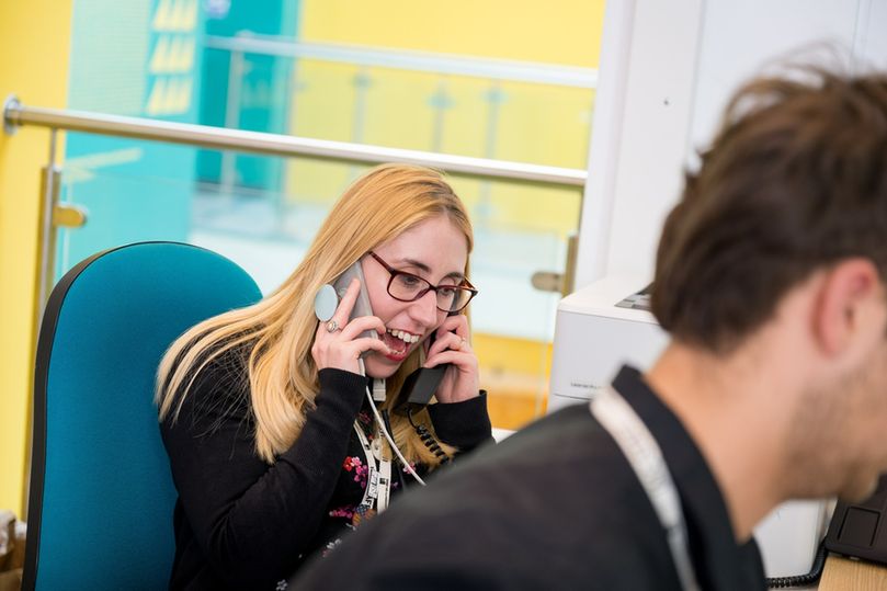 The IMC team member Alice holding two phones to both her ears.