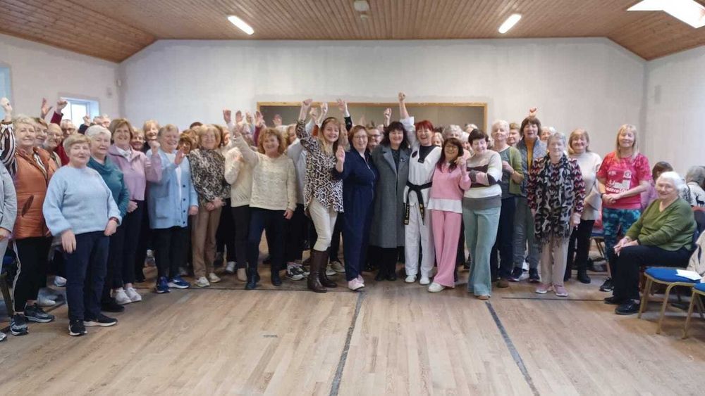 Large group of women assembled in a large hall and cheering.