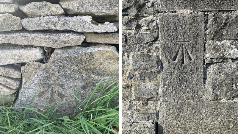 Benchmarks chiselled onto grey stone. The benchmark includes an upward pointing 'broad arrow' topped by a horizontal line cut known as the 'bench'.
