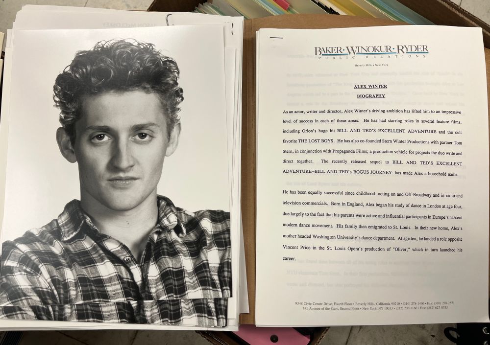 A headshot for Alex Winter, circa 1991, and the first page of a biography circulated by his PR reps. It reads:

BAKER WINOKUR RYDER
Beverly Hills • New York

ALEX WINTER
BIOGRAPHY
As an actor, writer and director, Alex Winter's driving ambition has lifted him to an impressive level of success in each of these areas. He has had starring roles in several feature films, including Orion's huge hit BILL AND TED'S EXCELLENT ADVENTURE and the cult favorite THE LOST BOYS. He has also co-founded Stern Winter Productions with partner Tom Stem, in conjunction with Propaganda Films; a production vehicle for projects the duo write and direct together.
The recently released sequel to BILL AND TED'S EXCELLENT ADVENTURE-BILL AND TED's BOGUS JOURNEY--has made Alex a household name.
He has been equally successful since childhood--acting on and Off-Broadway and in radio and television commercials. Born in England, Alex began his study of dance in London at age four, due largely to the fact that his parents were active and influential participants in Europe's nascent modern dance movement. His family then emigrated to St. Louis. In their new home, Alex's mother headed Washington University's dance department. At age ten, he landed a role opposite Vincent Price in the St. Louis Opera's production of "Oliver," which in turn launched his career.