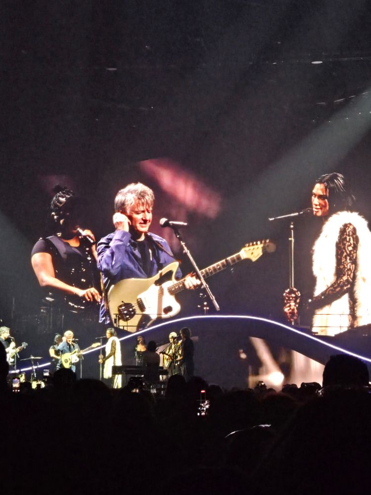 Kiwi legend Neil Finn with his guitar singing Crowded House classic Don't Dream It's Over with Dua Lipa at her show in Auckland.