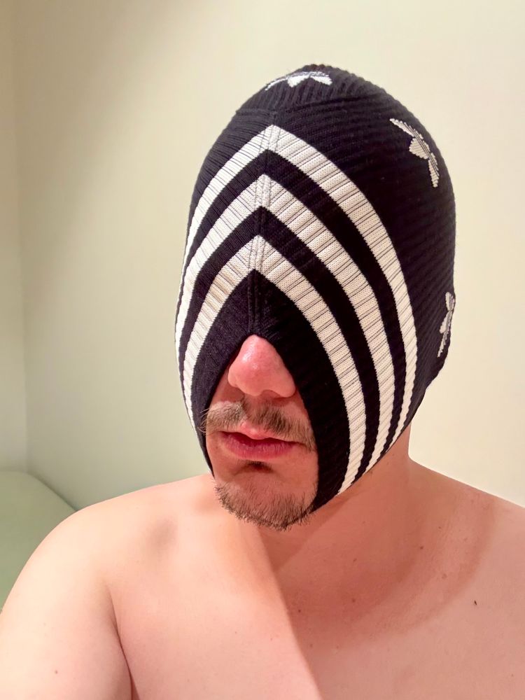 Selfie of me naked wearing a balaclava hood made out of black Adidas socks. The hood only has one big opening for the mouth around the nose and the chin.