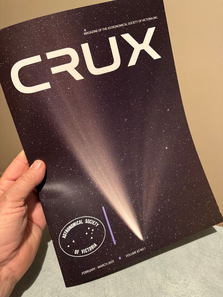 Holding the The Crux magazine showing front cover image of a comet. 