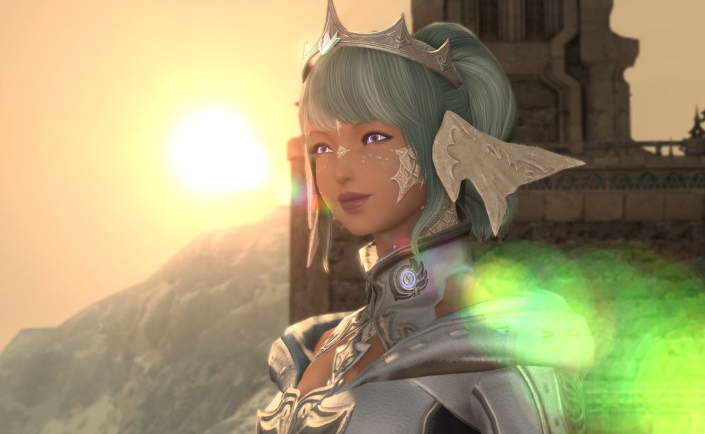 a green-haired Au Ra in silver crown and tech gear standing in front of a setting sun with a bright green lens flair. Her freckles are a light teal and reminiscent of her Azem's freckle patterns.