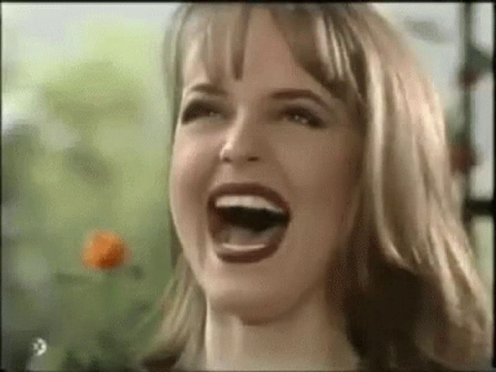 a woman is laughing with her mouth open in a video .