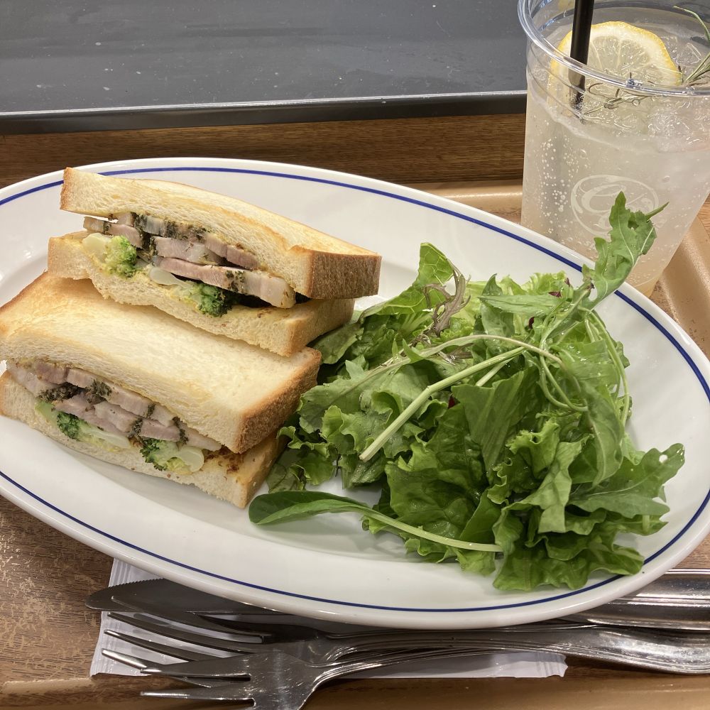 茶色いトレイの上にカトラリー、サンドイッチとサラダの乗った皿、ドリンクが置かれている
森林大猪肉をイメージしたサンドイッチと柚子のハーブティースパークリング