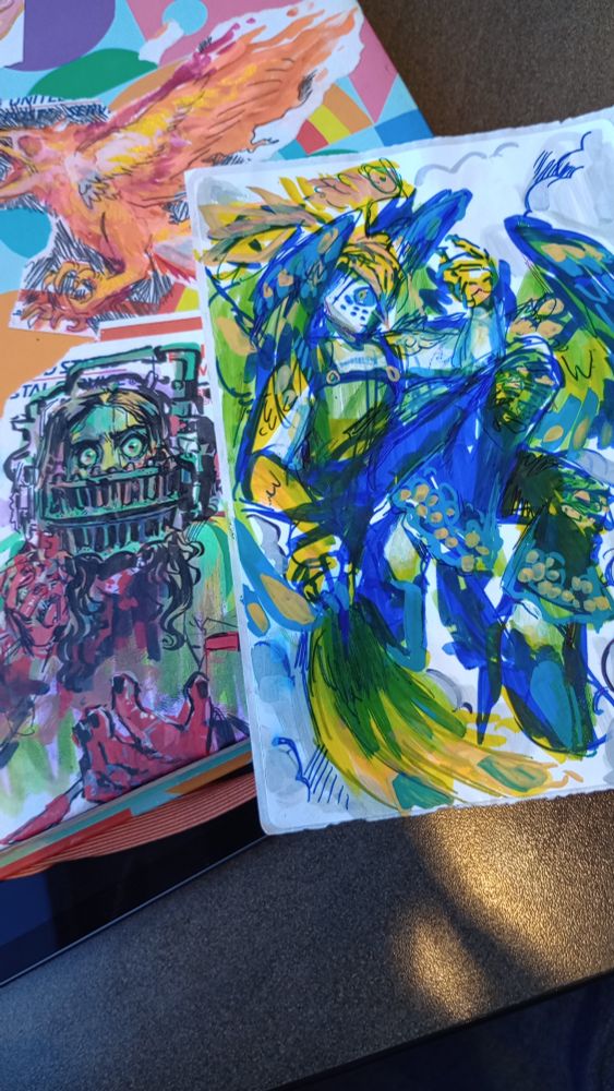 3 drawings, Amanda from saw, a blue and green bird person, and a phoenix (the Phoenix one's old but it's in frame)