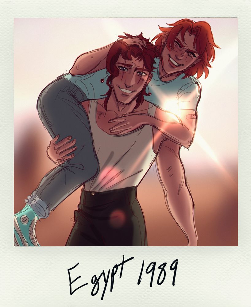 A young man stands against a desert background at sunset in a Polaroid photo. He has red hair, a white tank top, green pants, and scars over his eyes, and he is smiling. He is also carrying another young man with jeans, teal converse and a teal shirt, and shoulder-length orange hair over his shoulder. The young man being carried is also smiling.