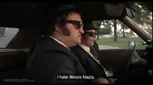 The image is from "The Blues Brothers" when they're stuck in traffic by a Illinois nazi march and Jake says "I hate Illinois Nazis."