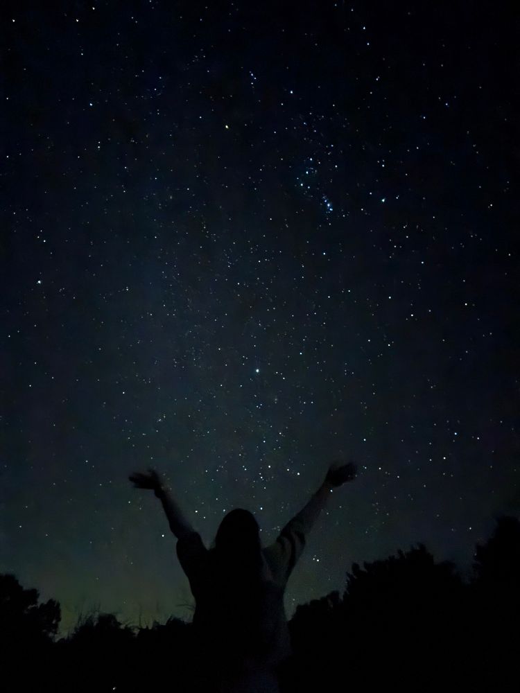 A photo of me with my arms up in front of a very starry sky.