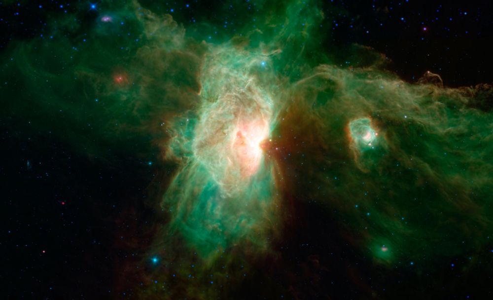 Spitzer Telescope image of the Horsehead Nebula. In visible-light images, the nebula has a distinctively dark and dusty horse-shaped silhouette, but when viewed in infrared light, dust becomes transparent and the nebula appears as a wispy arc. Here, blue represents light emitted at a wavelength of 3.6-microns, and cyan (blue-green) represents 4.5-microns, both of which come mainly from hot stars. Green represents 8-micron light and red represents 24-micron light. Relatively cooler objects, such as the dust of the nebulae, appear green and red.