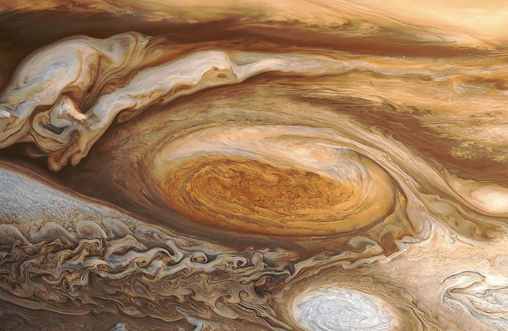 A close up of Jupiter’s Great Red Spot. Swirling white and brown clouds can be seen around it.

Processing: Bjorn Jonsson