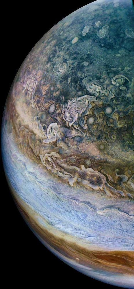 A close up of Jupiter and its swirling storms and atmosphere in many colors - white, blue, orange, brown.