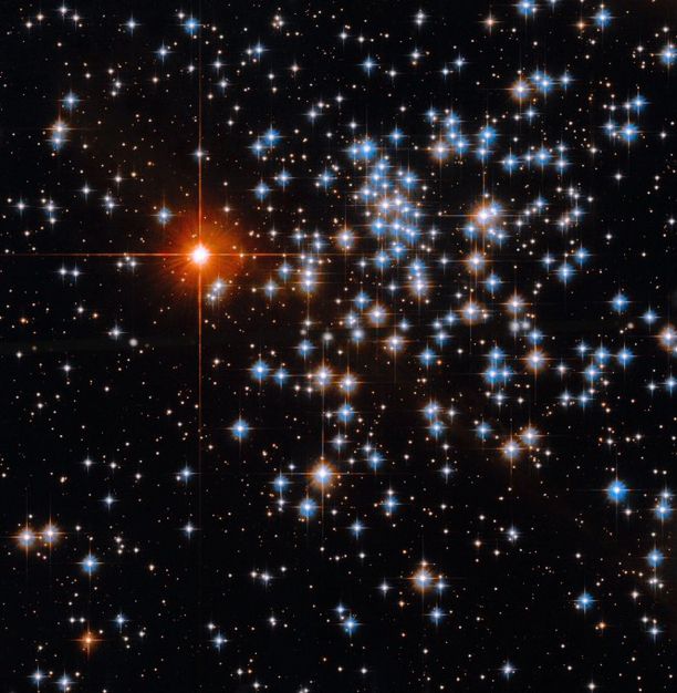 Several stars with pointed diffraction spikes gleam in shades of white, orange, and blue against a black backdrop of space.
