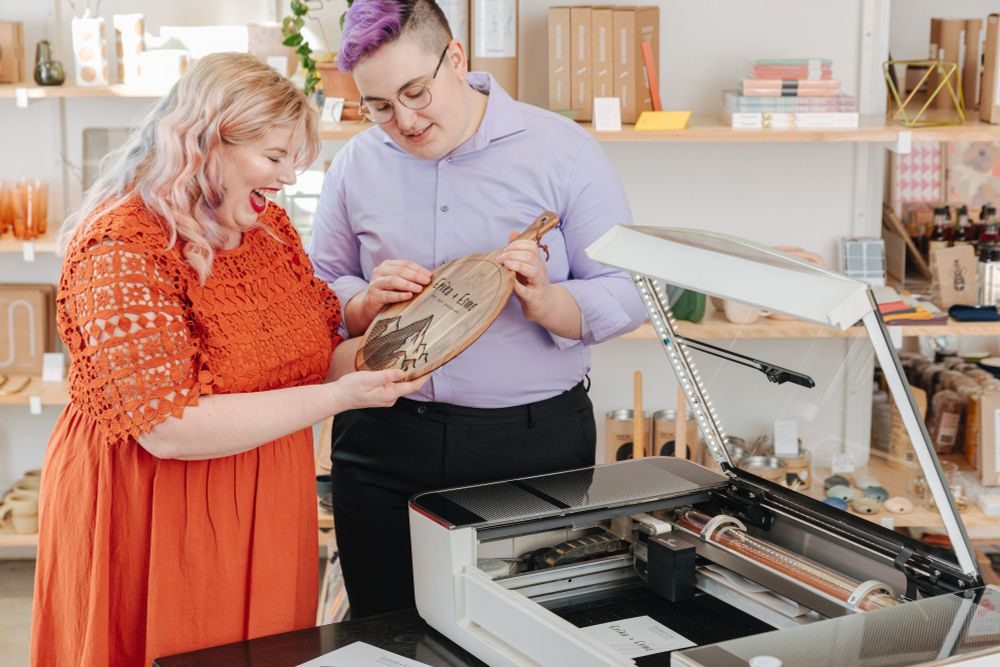 Photo of two crafters examining a cutting board they engraved with their Glowforge Pro.