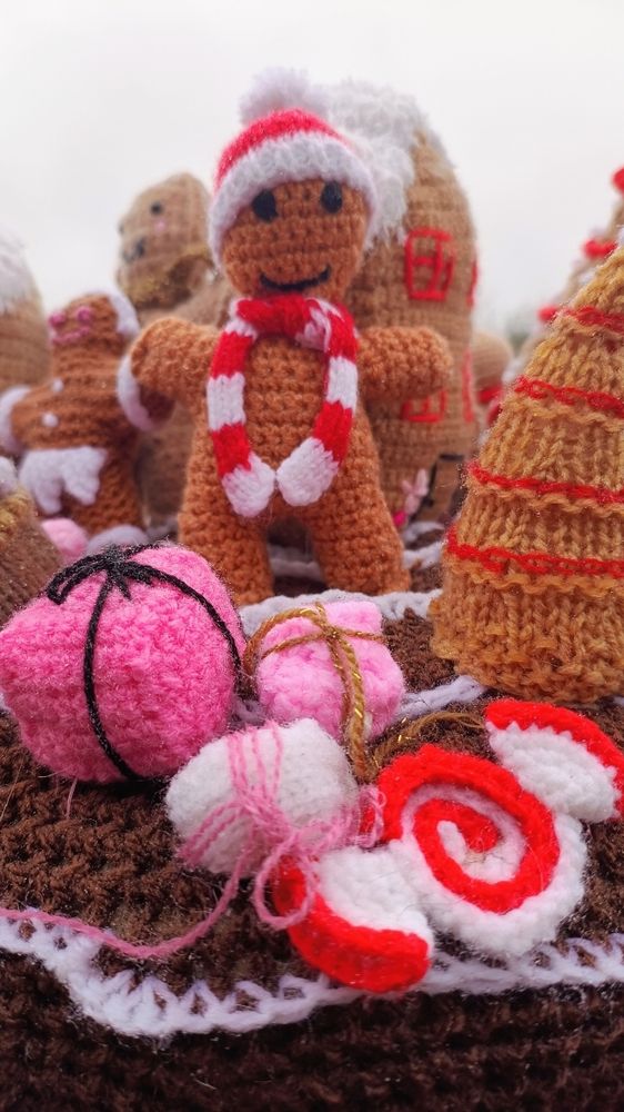 Photograph of a hand made knitted gingerbread man wearing a Father Christmas bobble hat and scarf 
