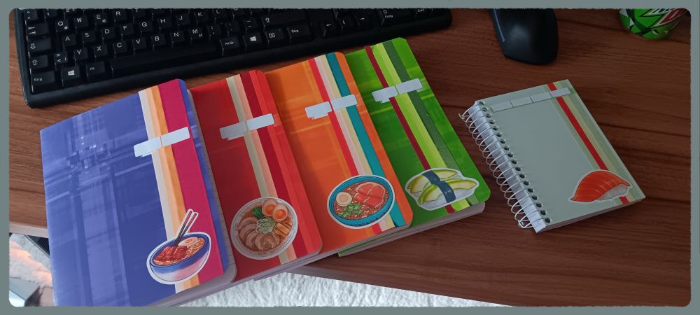 A collection of notebooks that I put some washi tape and some food stickers on. There's a blue-ish/purple one, a red one, an orange one and a green one as well as a smaller light mint one.