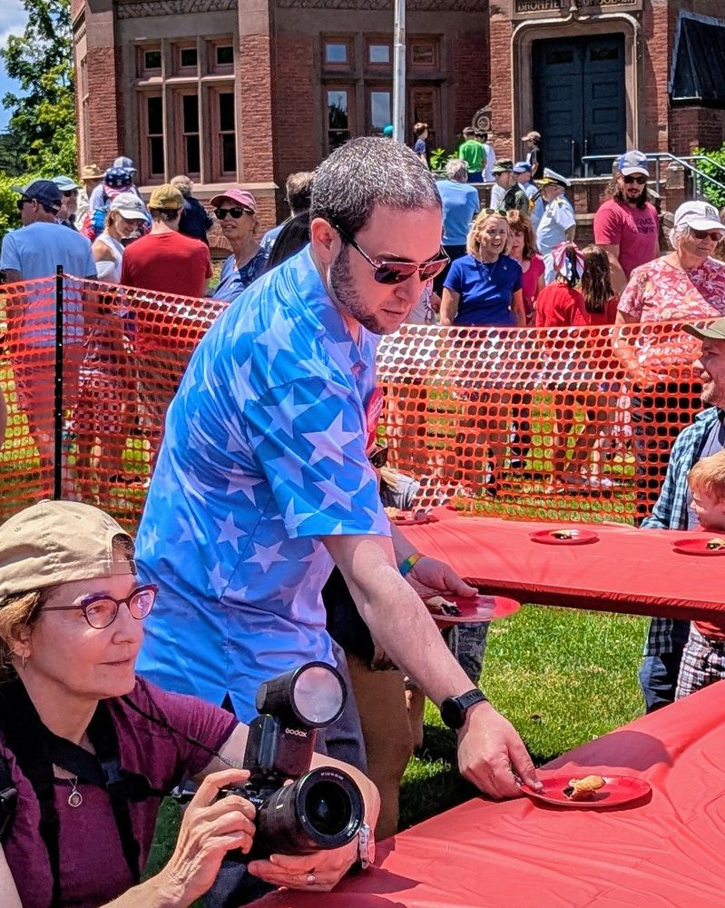 Alex distributing a the pies while a photographer gets ready for the event