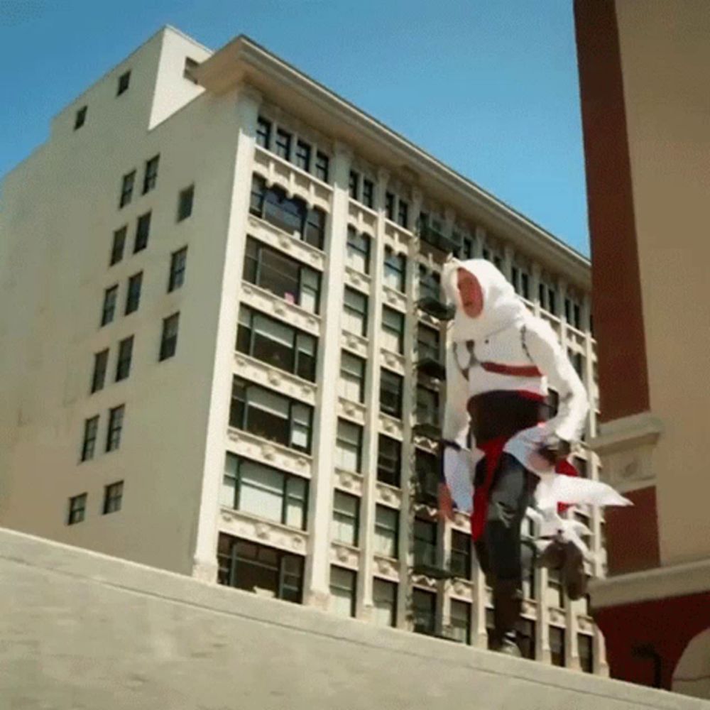 a man in a hooded costume is jumping over a ledge