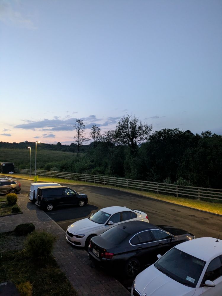 picture of a parking lot at just after 10pm. the sun is just beginning to set in earnest, the sky is still bright 
