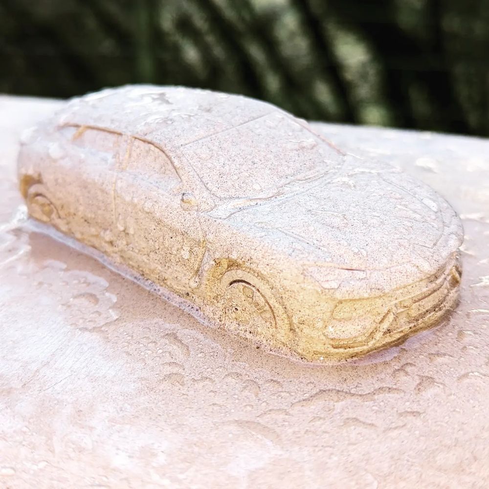 Stone carving of a car, sitting on top of a stone sculpture.