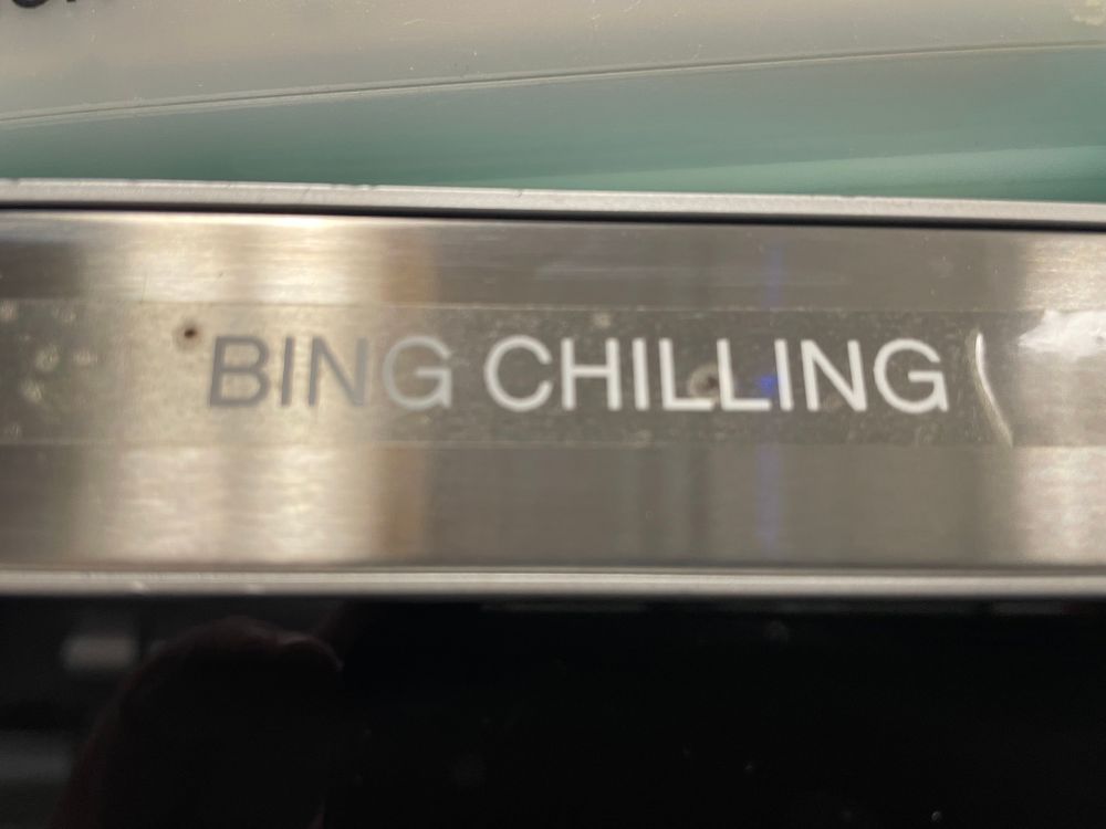A transparent label with the words "BING CHILLING" affixed to a shiny metal surface.