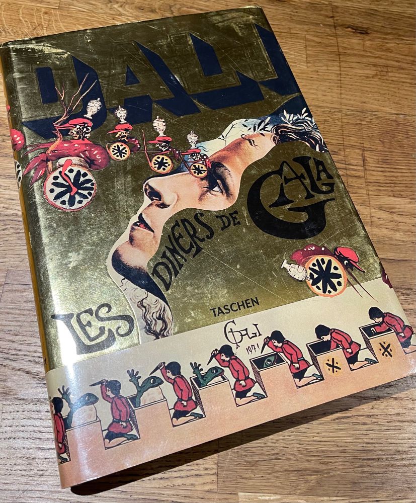 Book: Salvador Dali’s “les diners de gala”. 
Gold, shiny cover with elaborate illustrations