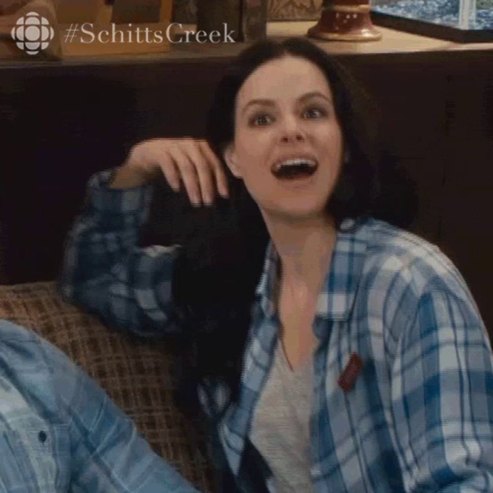 a woman in a blue plaid shirt is sitting on a couch and smiling ..