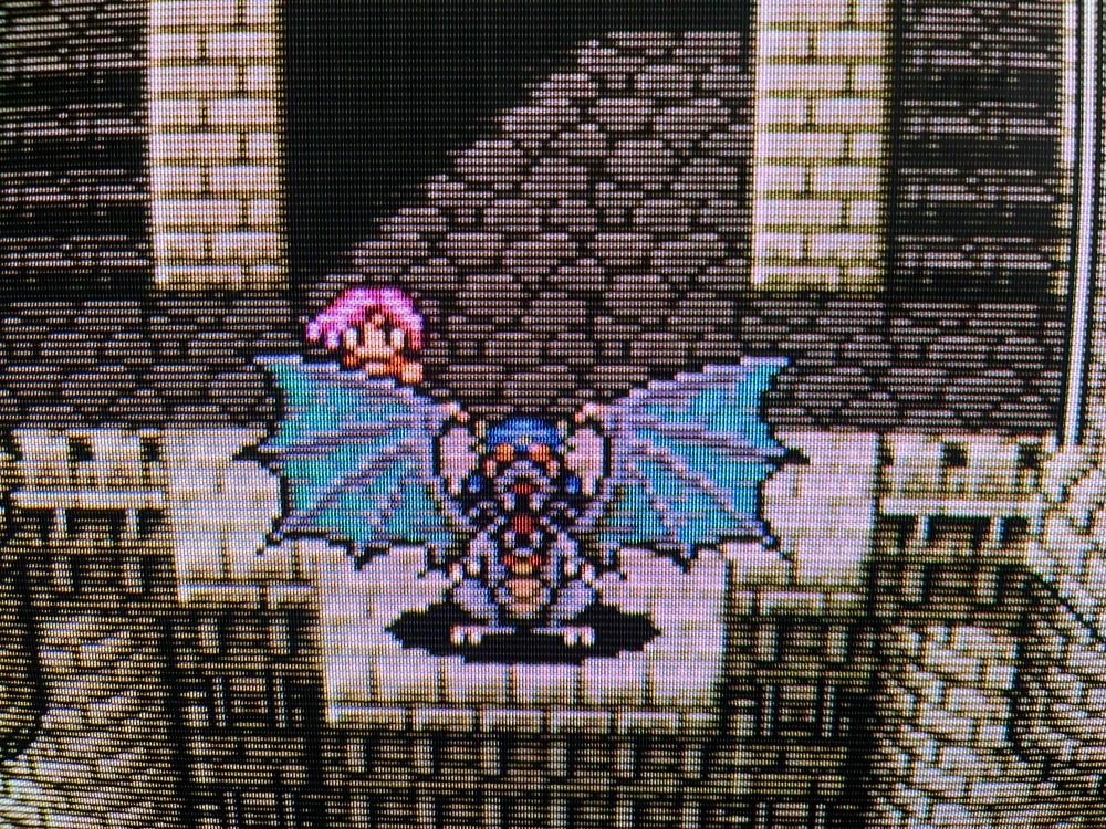 A screenshot of Final Fantasy V on a CRT. A grey dragon stretches its blue wings on the precipice of a castle’s upper floors.