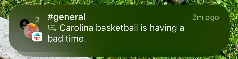 Phone notification showing an Apple Intelligence summary of messages from Slack. The summary reads, “Carolina basketball is having a bad time.”