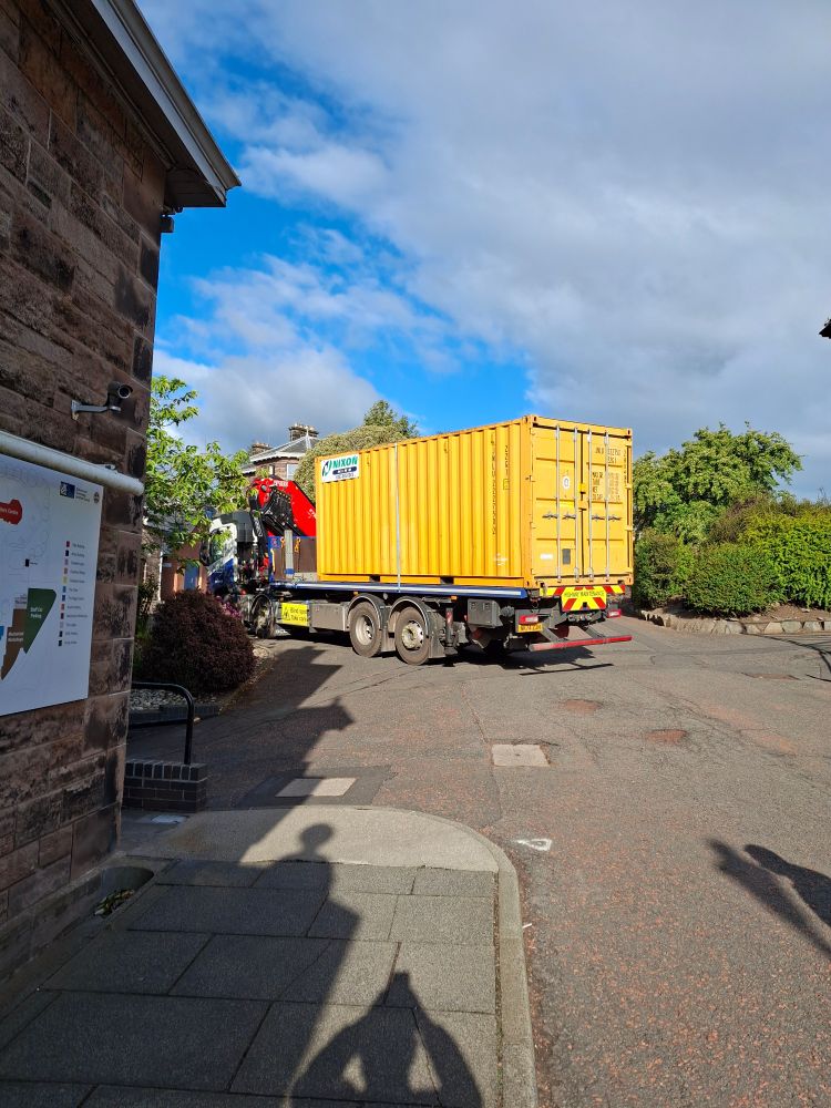 Yellow portacabin on the back of a lorry being carefully moved into place behind the lodge at the ROE.