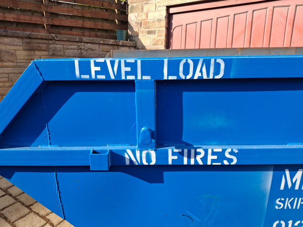Sign on the side of a skip that says "Level Load and then on a separate line "No Fires"