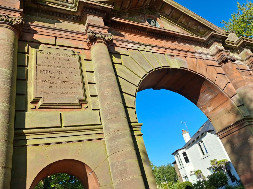 Blue sky seen through an archway the inscription on the arch reads:

"THIS ARCH IS ERECTED 12th SEPTEMBER 1888 TO COMMEMORATE THE WORK & CHARACTER.OF GEORGE HARRISON Kt. MP. LLD WHOSE LIFE WAS DEVOTED TO THE PUBLIC GOOD BORN 1812 : DIED I885"

Never realised the beatles were that long ago. 

