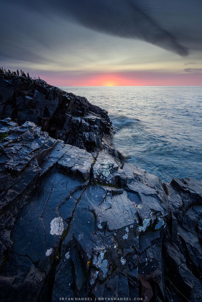 Sunrise over a rocky basalt shoreline and Lake Superior.