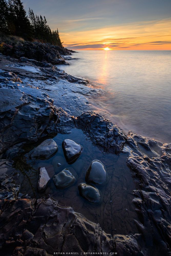 Sunrise over a rocky basalt shoreline and Lake Superior.