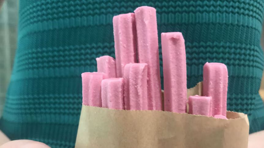 pink musk sticks coming out of a brown paper bag